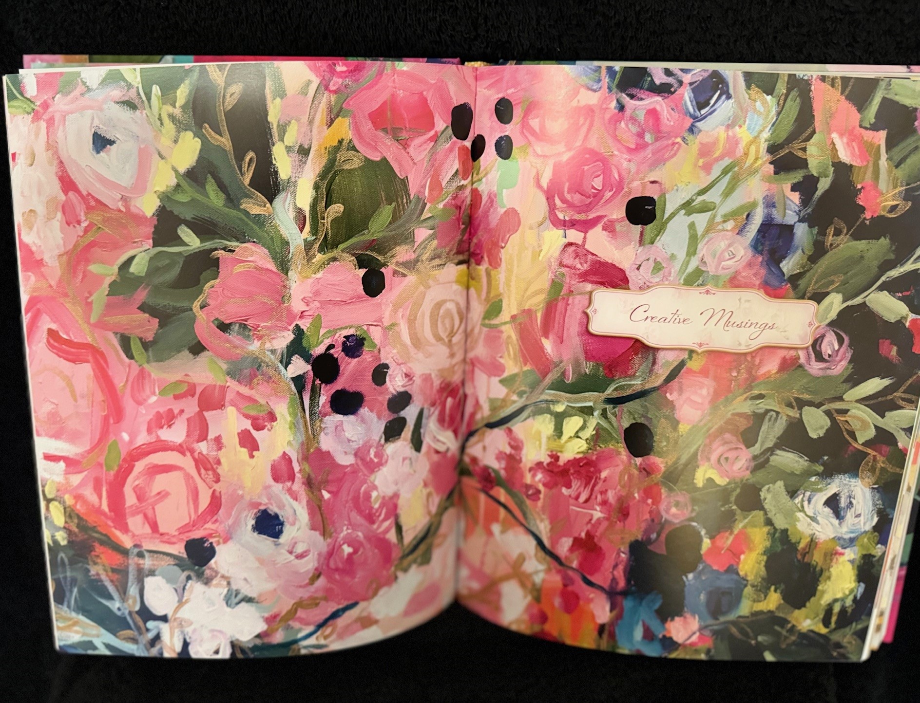 Open art book showing a pink floral painting printed on matte paper